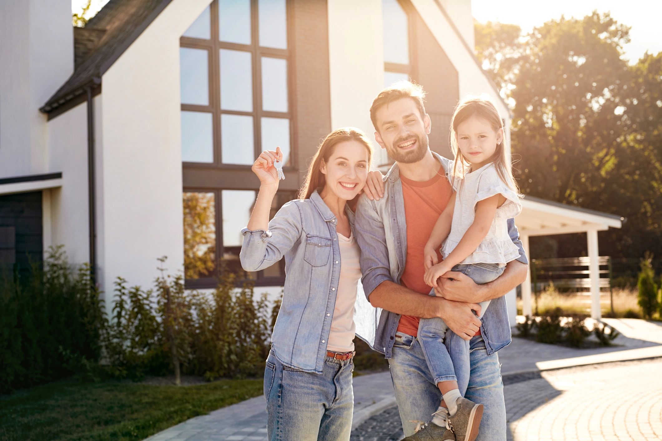 Happy homeowners holding keys outdoors