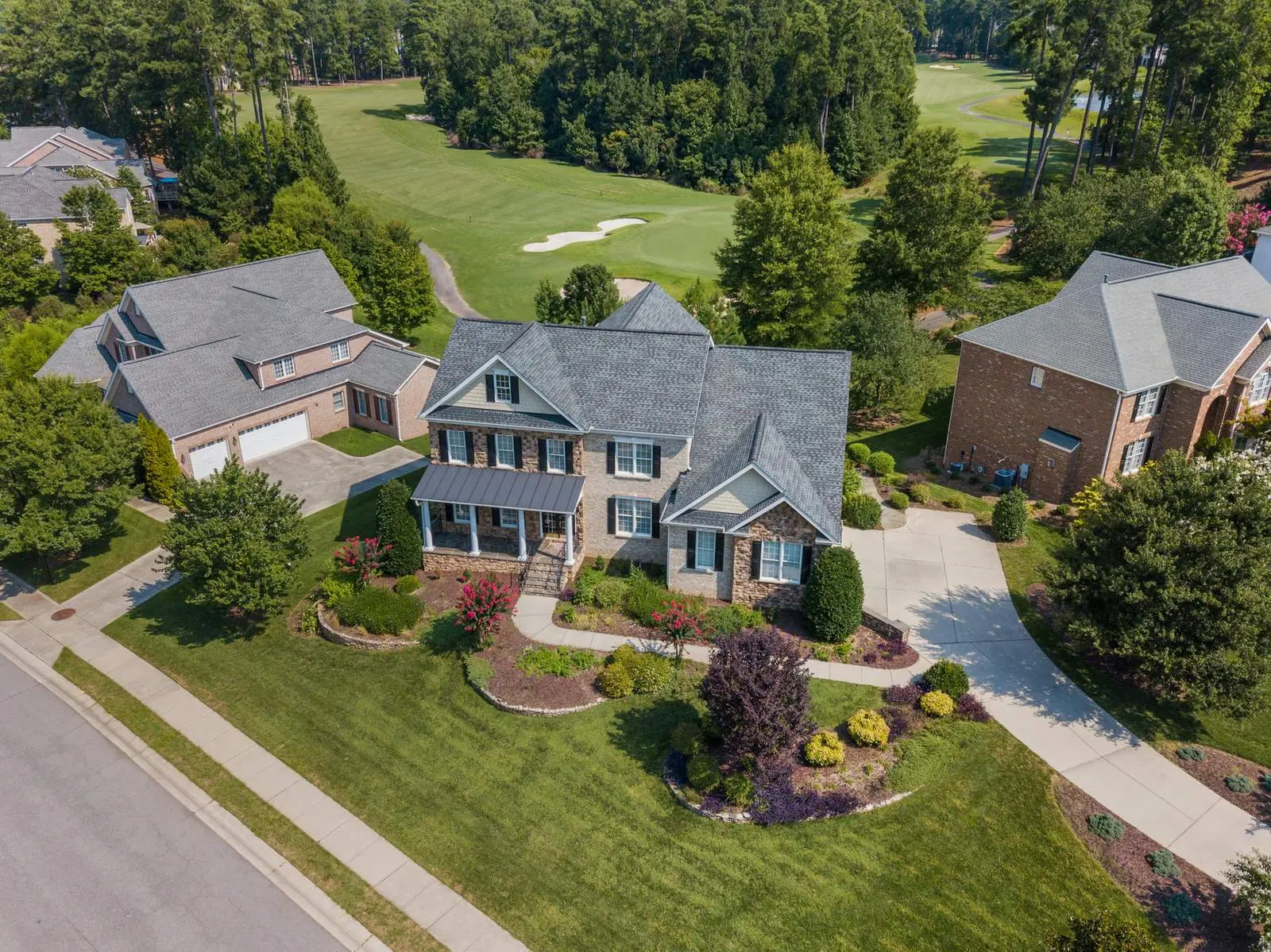 Aerial view of an upscale Northern Virginia neighborhood with large brick homes, manicured lawns, and a golf course in the background